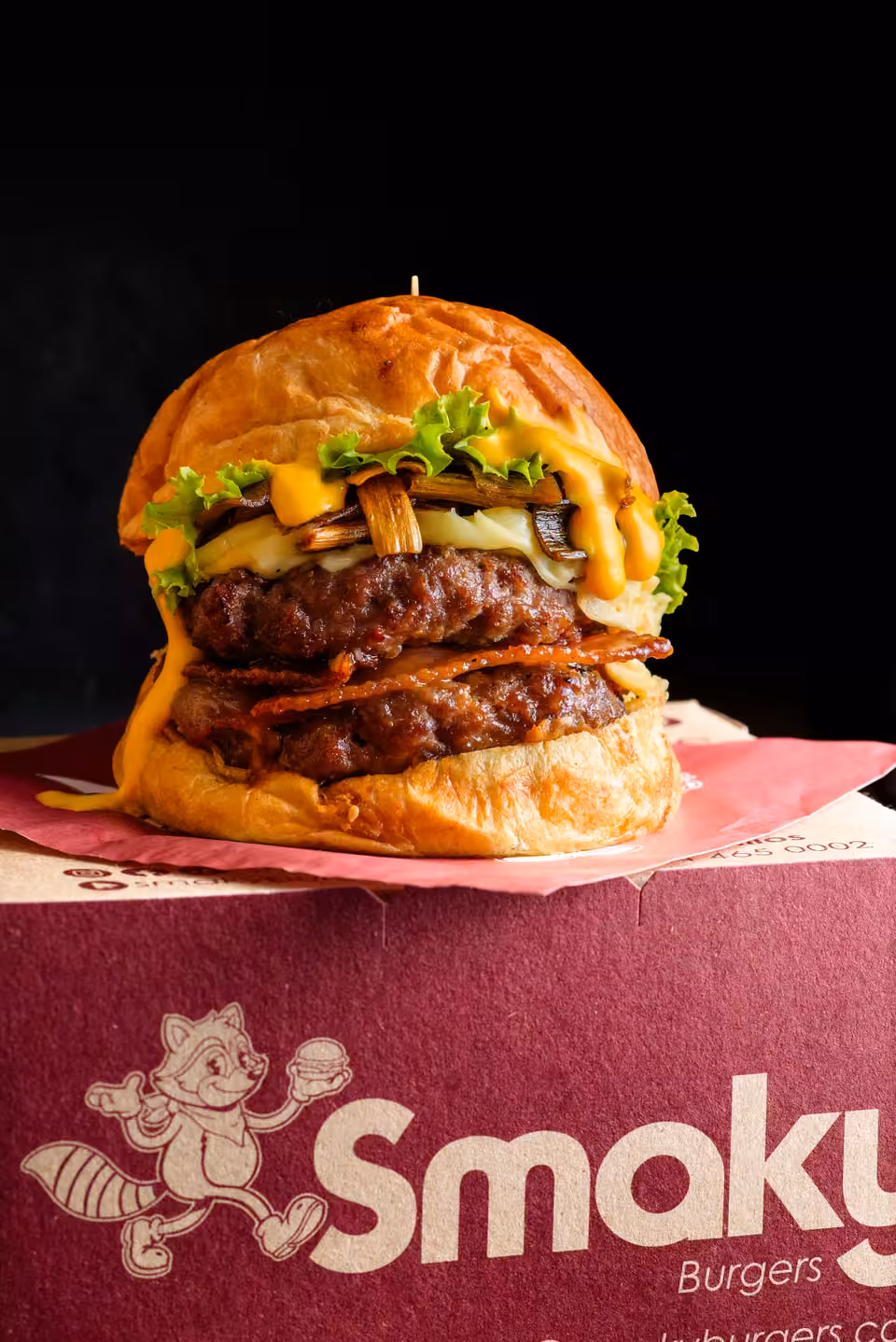 Hamburguesa Smaky de doble carne sobre una caja de Smaky Burgers