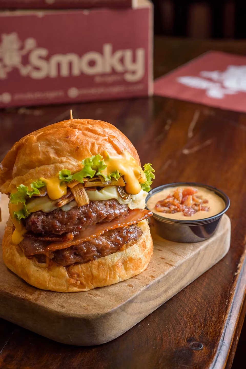 Hamburguesa Smaky con salsa y tocineta sobre una tabla